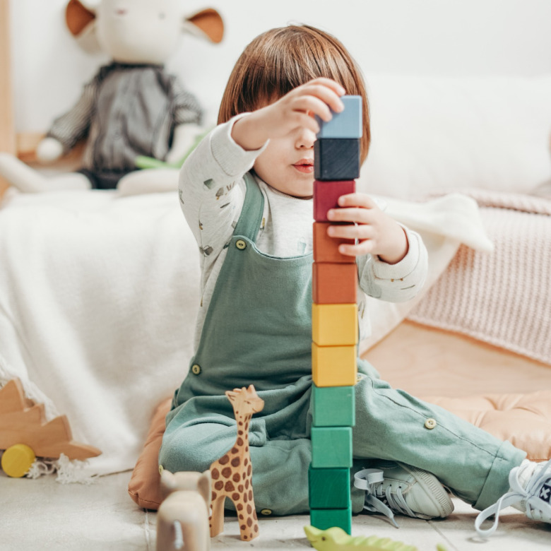 Young child participating in ABA therapy in Chattanooga, stacking colorful blocks to develop fine motor skills, problem-solving, and cognitive growth in a supportive environment.